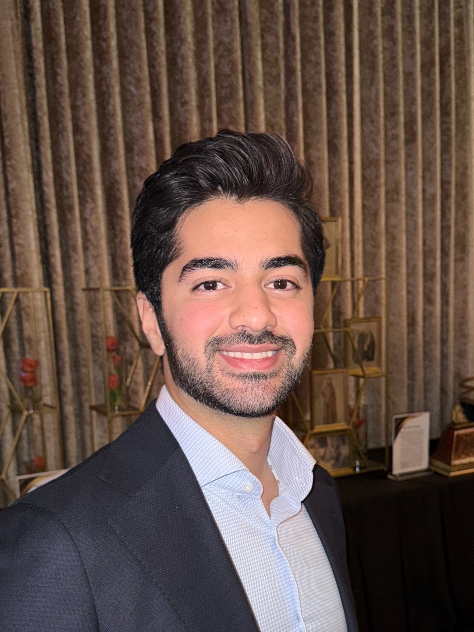 Sina Zhaleh smiling, wearing a navy jacket and light blue shirt